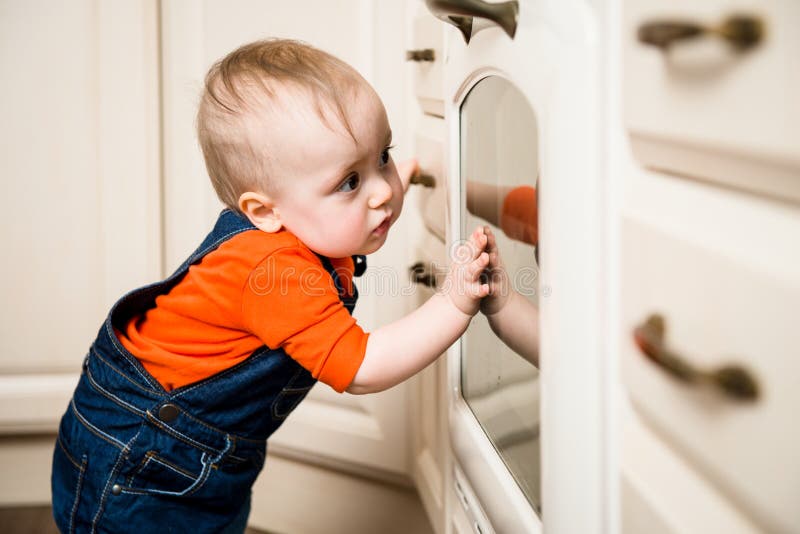 Baby watching inside kitchen oven royalty free stock images