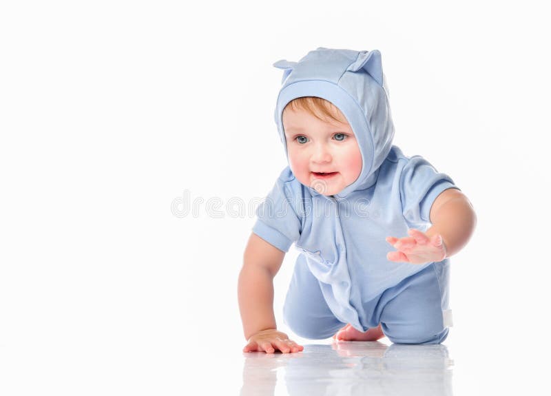 Baby wearing funny suit crawling on studio floor. Cute little kid in a funny blue suit and a hood with ears on his head, crawling towards the camera on the royalty free stock photography Baby wearing funny suit crawling on studio floor. Cute little kid in a funny blue suit and a hood with ears on his head, crawling towards the camera on the royalty free stock photography