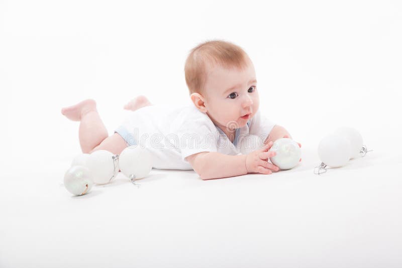 Baby on a white background playing with Christmas toys