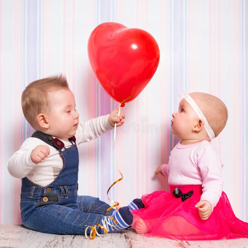 Babyjongen die een hartballon geven aan het meisje stock afbeelding Babyjongen die een hartballon geven aan het meisje stock afbeelding