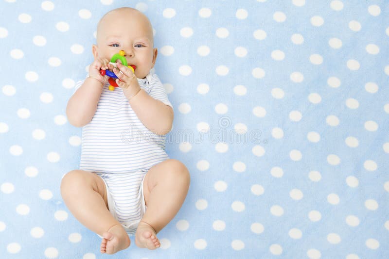 Babyjongen met Teether Toy In Mouth Lying over Blauwe Gelukkige Achtergrond, stock fotografie Babyjongen met Teether Toy In Mouth Lying over Blauwe Gelukkige Achtergrond, stock fotografie