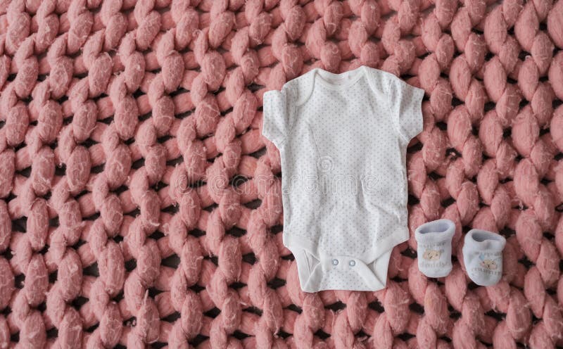 Babykleren en schoenen voor pasgeboren in pastelkleuren op roze merinoswoldeken Reeks babykleren Lichaam en buiten stock fotografie Babykleren en schoenen voor pasgeboren in pastelkleuren op roze merinoswoldeken Reeks babykleren Lichaam en buiten stock fotografie