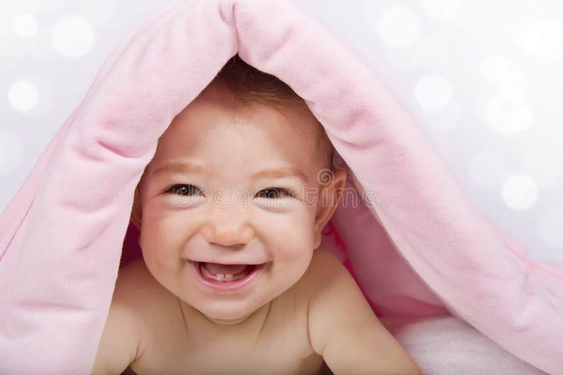 Babymeisje onder roze deken met glimlach royalty-vrije stock fotografie Babymeisje onder roze deken met glimlach royalty-vrije stock fotografie