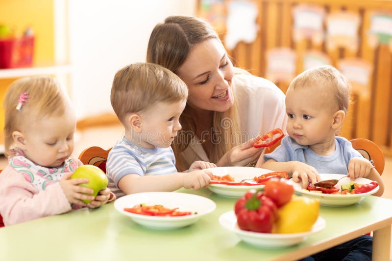 Babys van het babysitter de voedende kinderdagverblijf De peuters eten gezond voedsel in opvang stock foto Babys van het babysitter de voedende kinderdagverblijf De peuters eten gezond voedsel in opvang stock foto