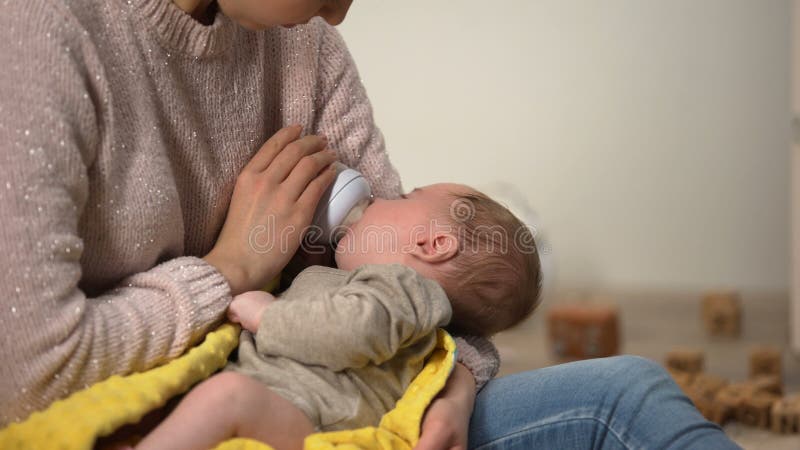 Babysitter alimentant la petite fille adorable de la bouteille, formule anticolic de lait clips vidéos