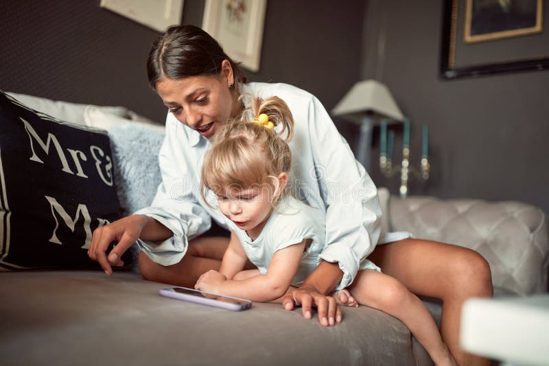 Babysitter con il bambino che guarda in telefono cellulare fotografia stock Babysitter con il bambino che guarda in telefono cellulare fotografia stock