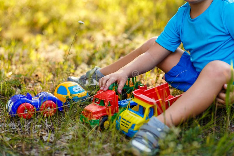 Babyspiele mit Plastikmaschinen auf dem Gras stockbilder Babyspiele mit Plastikmaschinen auf dem Gras stockbilder