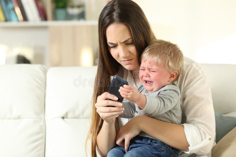 Babywoedeaanval die met zijn moeder voor een slimme telefoon vechten royalty-vrije stock fotografie Babywoedeaanval die met zijn moeder voor een slimme telefoon vechten royalty-vrije stock fotografie