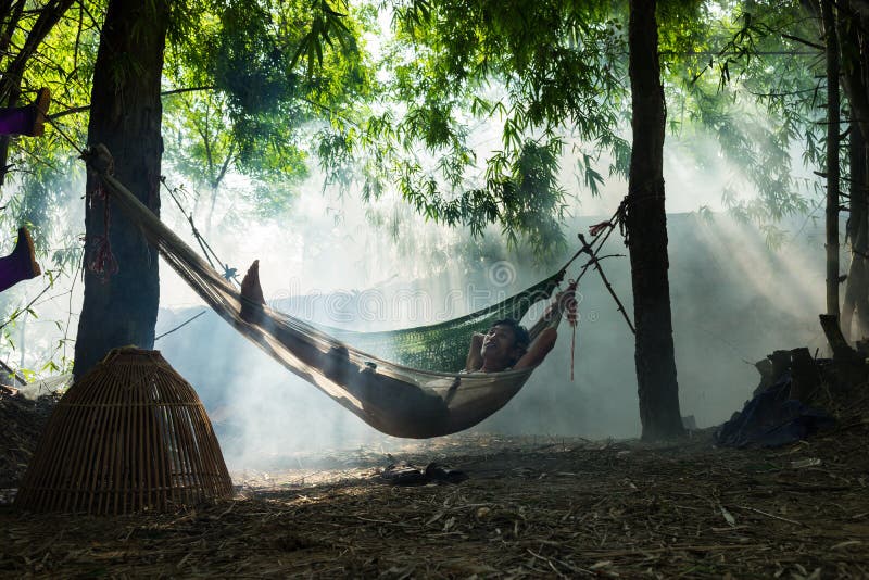 Bac Ninh, Vietnam - 29 de mayo de 2016: Un hombre que toma una rotura al mediodía en la hamaca en la sombra del árbol por el río fotografía de archivo Bac Ninh, Vietnam - 29 de mayo de 2016: Un hombre que toma una rotura al mediodía en la hamaca en la sombra del árbol por el río fotografía de archivo