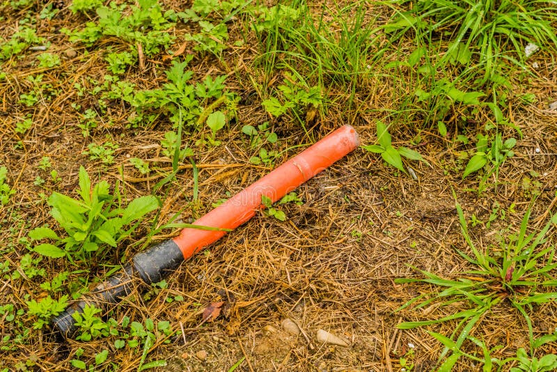 Bastone segnaletico rosso in plastica rotto e abbandonato immagini stock