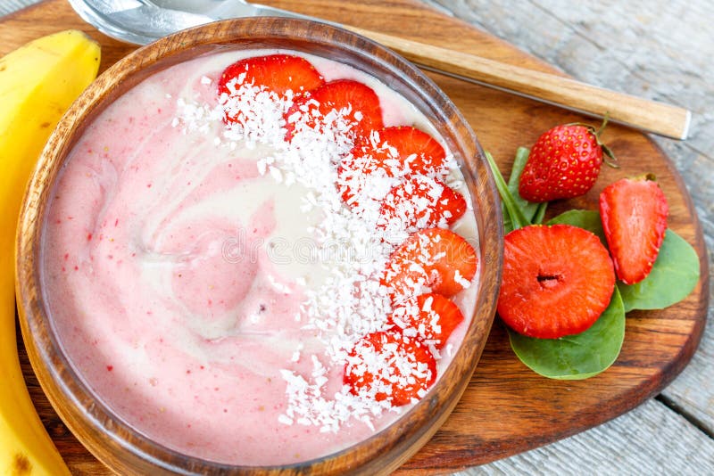 Bacia brilhante do batido da morango-banana do verão com coco imagem de stock Bacia brilhante do batido da morango-banana do verão com coco imagem de stock