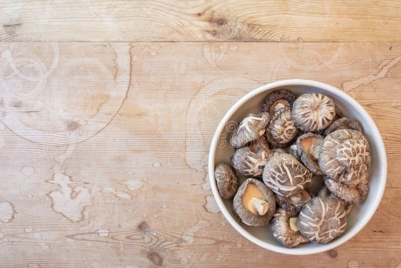 Bacia de cogumelos de shiitake secados, mais baixo direito, em uma tabela de madeira velha, espaço da cópia foto de stock royalty free Bacia de cogumelos de shiitake secados, mais baixo direito, em uma tabela de madeira velha, espaço da cópia foto de stock royalty free