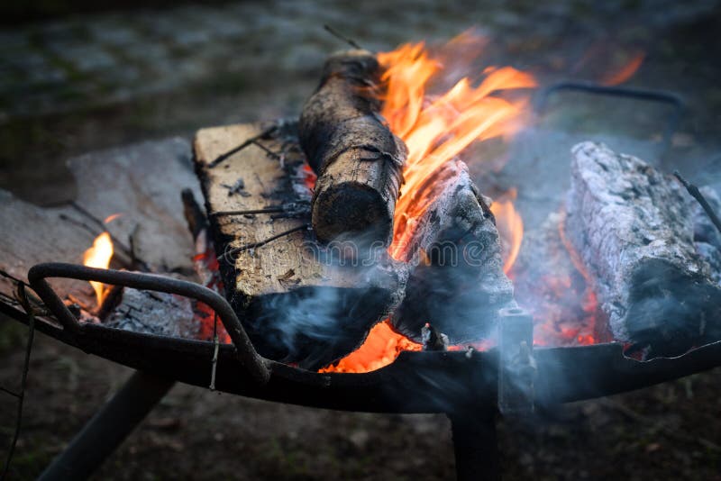 A bacia de fogo do ferro com logs de madeira de queimadura aquece-se no evento do ar livre