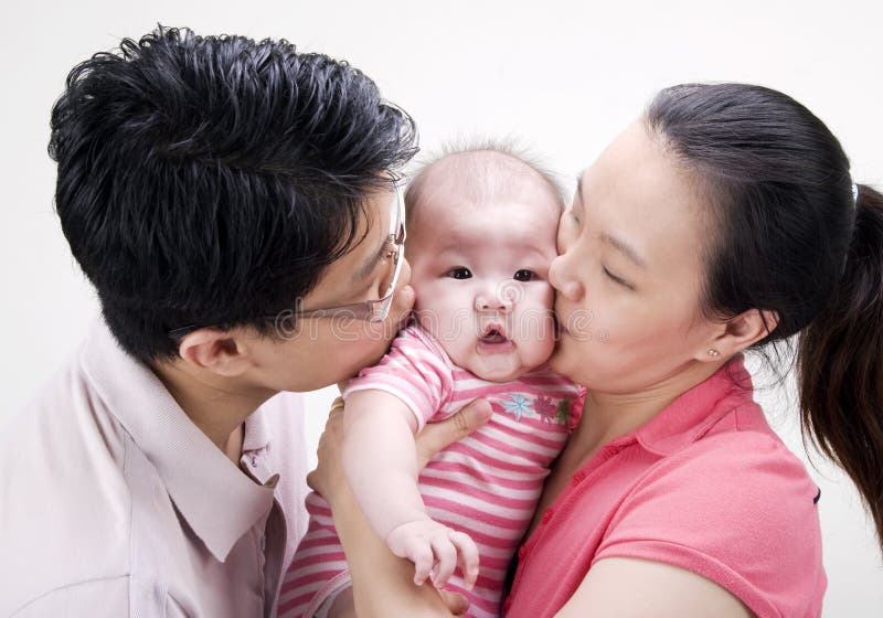 Asian parent kissing their 4 months old baby girl. Asian parent kissing their 4 months old baby girl