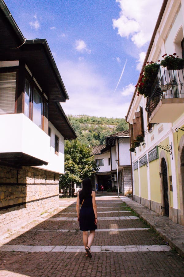 Back of a Girl Walking through the antique streets of a traditional village of Bulgaria in a blue dress stock photos Back of a Girl Walking through the antique streets of a traditional village of Bulgaria in a blue dress stock photos