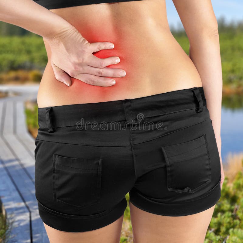 Back pain. Athletic woman in black sportswear standing and rubbing the muscles of her lower back, cropped torso portrait.Autumn Park Backgroun. Back pain. Athletic woman in black sportswear standing and rubbing the muscles of her lower back, cropped torso portrait.Autumn Park Backgroun