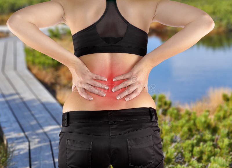 Back pain. Athletic woman in black sportswear standing and rubbing the muscles of her lower back, cropped torso portrait.Autumn Park Backgroun. Back pain. Athletic woman in black sportswear standing and rubbing the muscles of her lower back, cropped torso portrait.Autumn Park Backgroun
