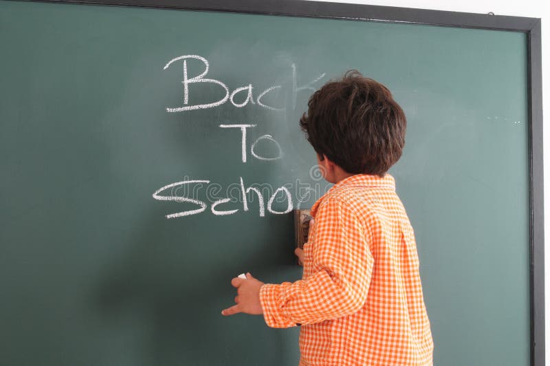 Preschooler writing on a chalkboard; Back to school. Preschooler writing on a chalkboard; Back to school