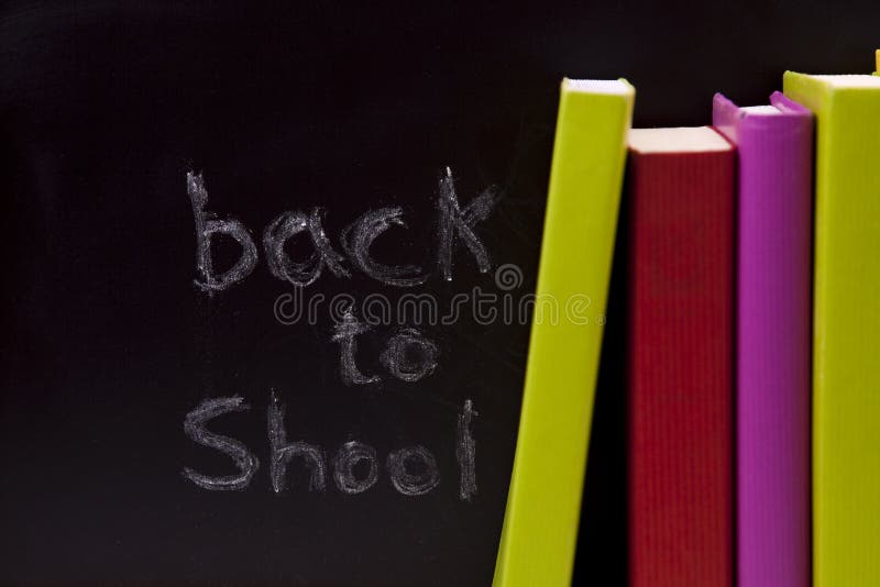 Back to school letters written on a blackboard with colorful books (selective focus)