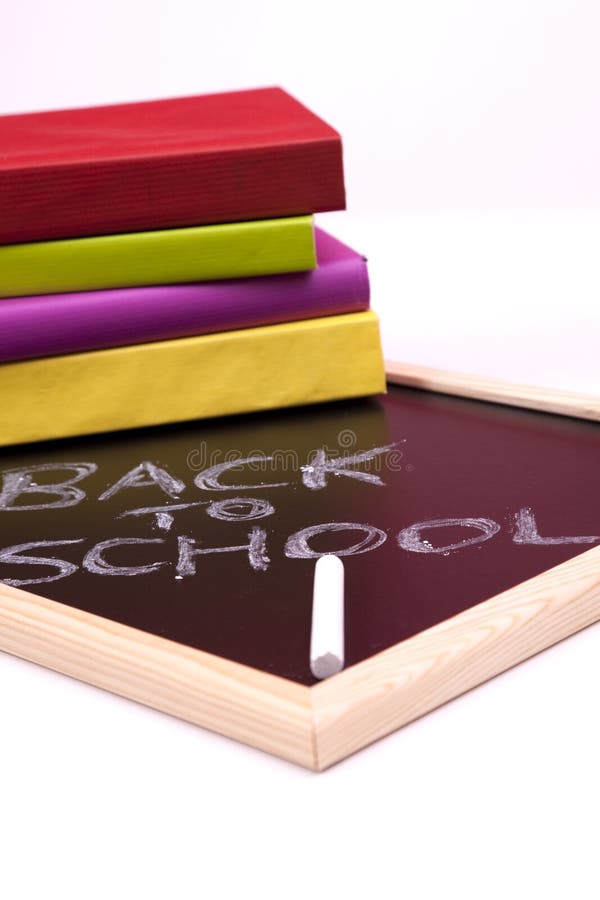 Back to school letters written on a blackboard with colorful books (selective focus)