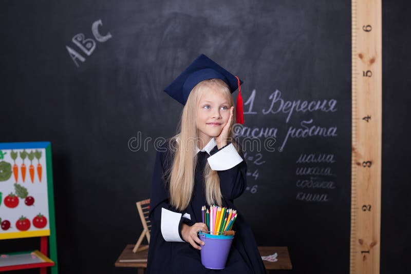 Back to school! Cheerful girl at school with pencils near the blackboard. School concept. On the blackboard in the Ukrainian langu stock photography Back to school! Cheerful girl at school with pencils near the blackboard. School concept. On the blackboard in the Ukrainian langu stock photography