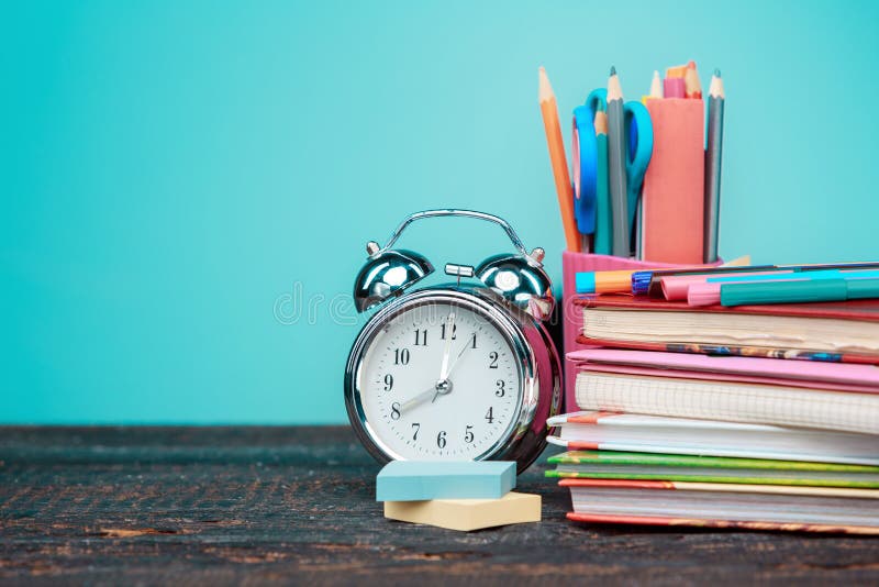 Back to School concept. Books, colored pencils and clock. Classroom, chalkboard.