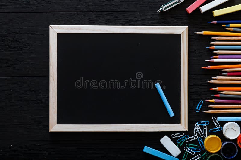 Back to school concept, creative workspace with colorful pencils, paints, frame and other school supplies for schoolwork on black desk, time to study, modern primary education, top view, copy space