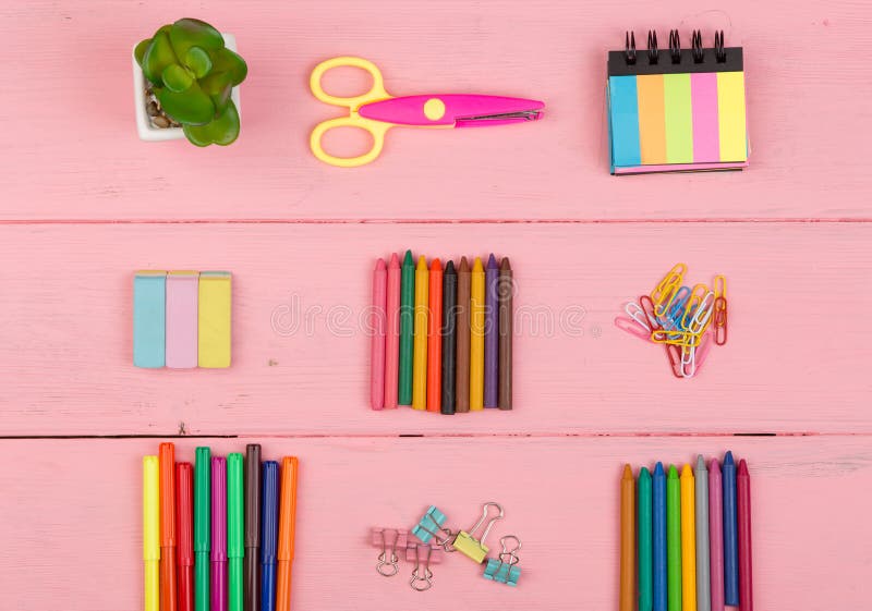 Back to school concept - school supplies: scissors, eraser, markers, crayons and other accessories on pink wooden table