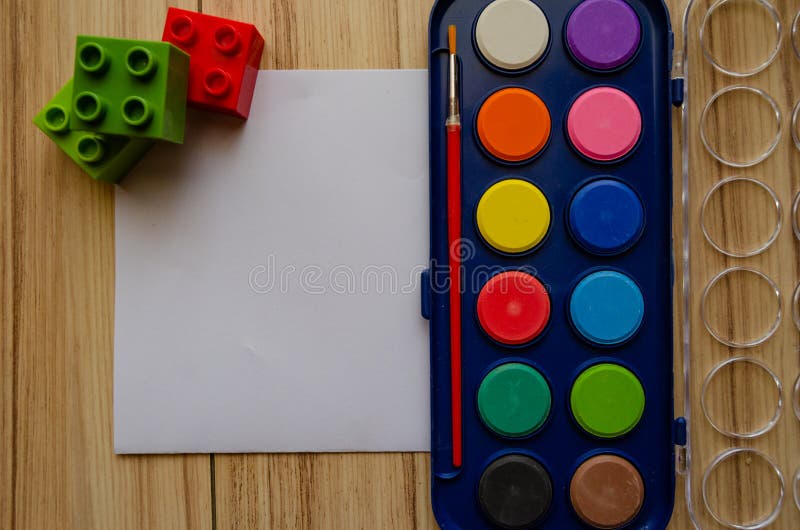 Back to school concept watercolor palet flat lay with blank paper and building blocks