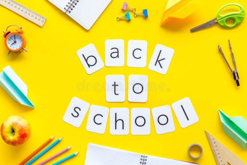 Back to school copy with stationary, apple, notebook and alarm clock on yellow student desk background top view royalty free stock photo Back to school copy with stationary, apple, notebook and alarm clock on yellow student desk background top view royalty free stock photo