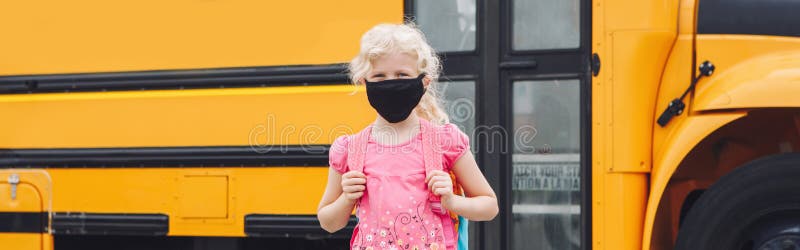 Back to school. Girl student wearing face mask near yellow bus. Kid with personal protective equipment on a face. New normal stock images Back to school. Girl student wearing face mask near yellow bus. Kid with personal protective equipment on a face. New normal stock images