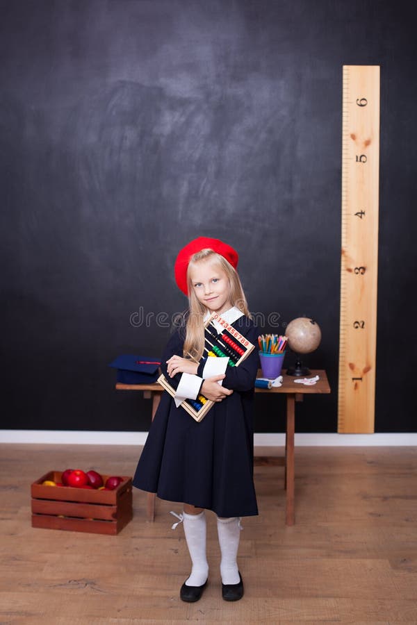Back to school! Little girl schoolgirl stands with bills and learns to count. School concept. Pupil answers at lesson. The kid is royalty free stock image Back to school! Little girl schoolgirl stands with bills and learns to count. School concept. Pupil answers at lesson. The kid is royalty free stock image