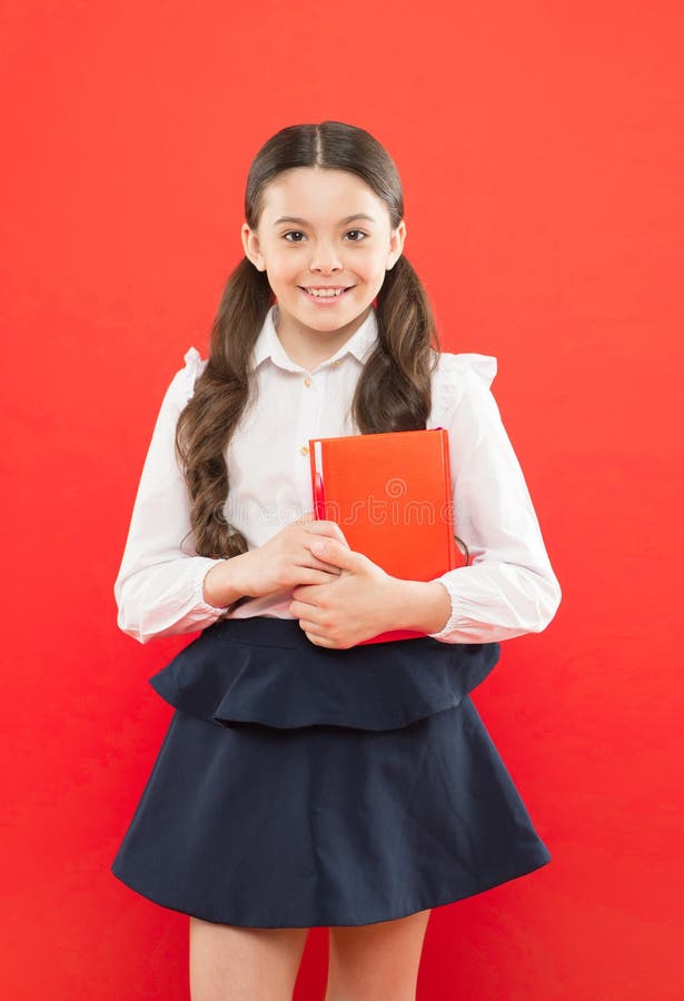 Back to school. This is my book. schoolgirl writing notes on orange background. small girl in school uniform. information form book. book lover. happy child with orange book. modern school education.