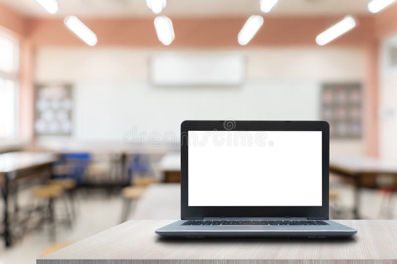 Back to school. Opened laptop with blank white screen on teachers desk in school auditorium, copy space