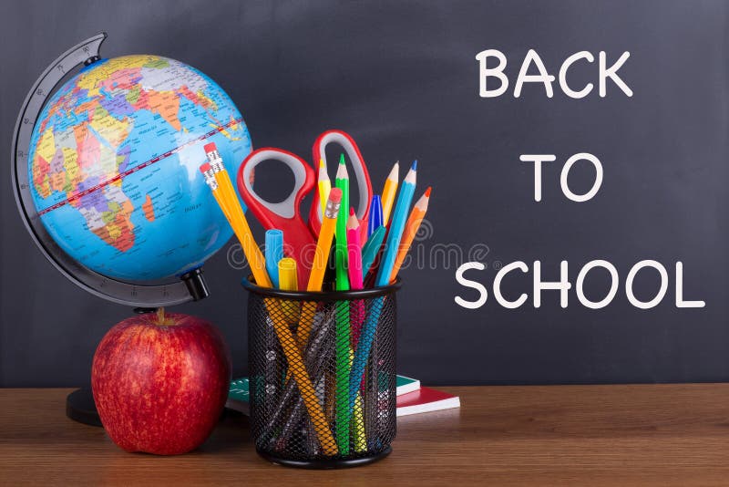 `Back To School` text written on a chalkboard with school accessories on a wooden desktop. `Back To School` text written on a chalkboard with school accessories on a wooden desktop