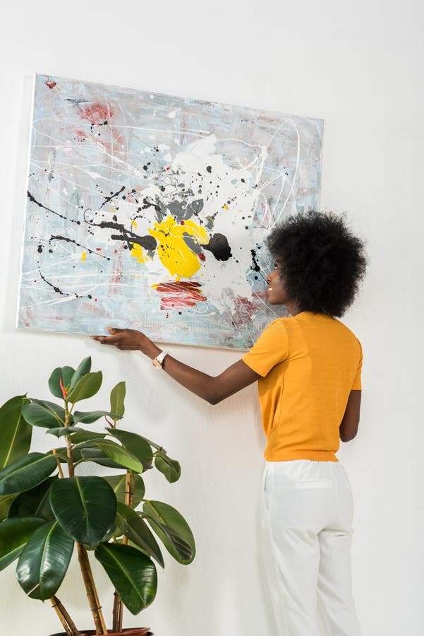 back view of african american hanging picture on wall