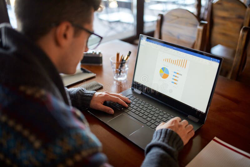Back view of caucasian businessman working on laptop with charts on the screen. Freelancer in glasses working on project royalty free stock photo Back view of caucasian businessman working on laptop with charts on the screen. Freelancer in glasses working on project royalty free stock photo