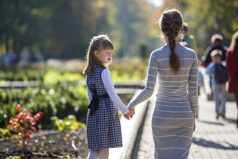 Back view of child girl and mother in dresses together holding hands on warm day outdoors on sunny background stock image Back view of child girl and mother in dresses together holding hands on warm day outdoors on sunny background stock image