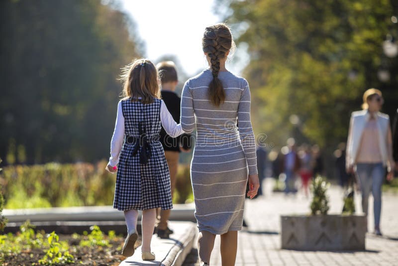 Back view of child girl and mother in dresses together holding hands on warm day outdoors on sunny background stock image Back view of child girl and mother in dresses together holding hands on warm day outdoors on sunny background stock image