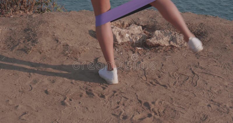 Woman exercising on sea shore cliff at sunrise