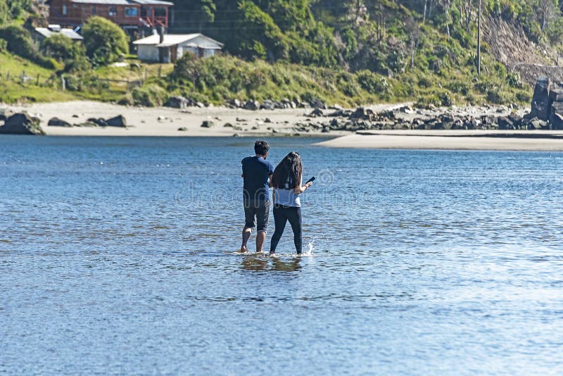 Back view of a couple walking in the water stock images