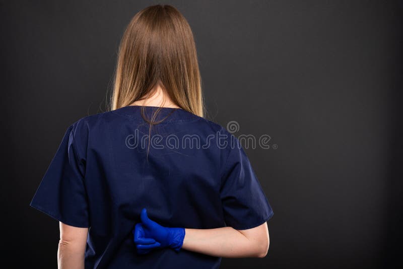 Back view of female dentist wearing scrubs showing like gesture stock photography