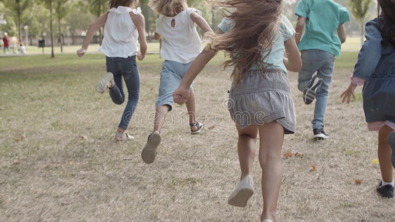 Back view of happy children competing in speed in park