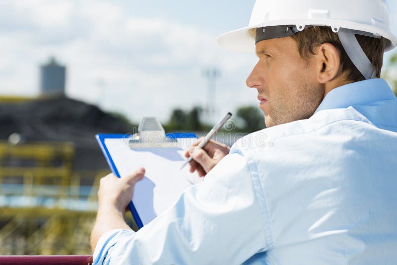 Back view of male architect with clipboard at construction site royalty free stock image