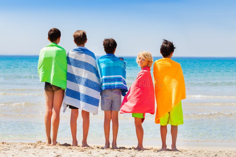 Boys dry off with beach towel after sea swimming