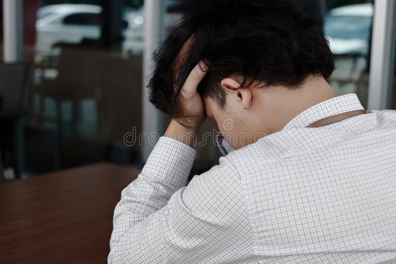 Back view of sad depressed young Asian business man covering face and cry.