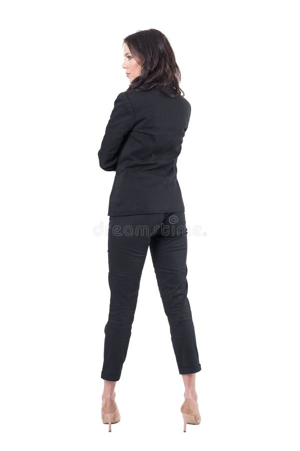 Back view of serious elegant woman in black suit looking away with crossed arms