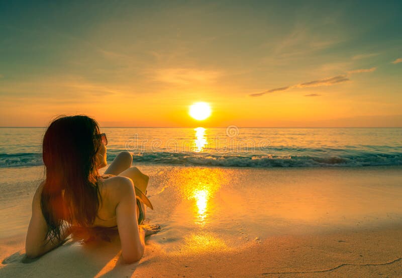 Back view of sexy, enjoy and relax woman wear bikini lying on sand beach with straw hat relax and enjoy holiday at tropical sea