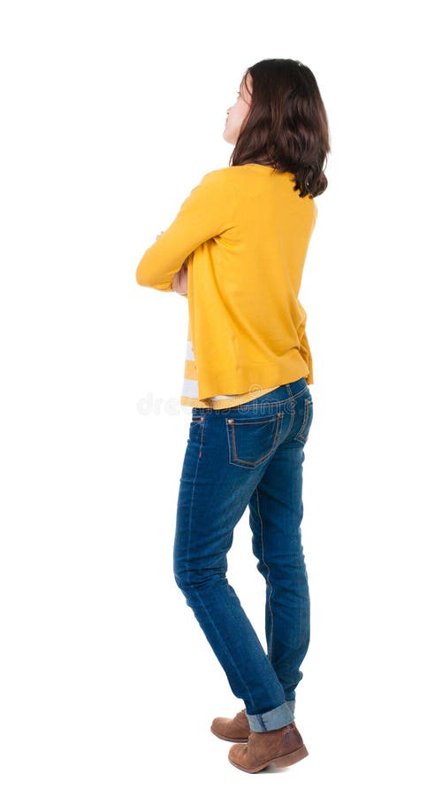 Back view of standing young beautiful brunette woman in yellow pullover. girl watching. Rear view people collection. backside view of person. Isolated over white background. Thoughtful girl in a yellow jacket unbuttoned looking up with his arms crossed.