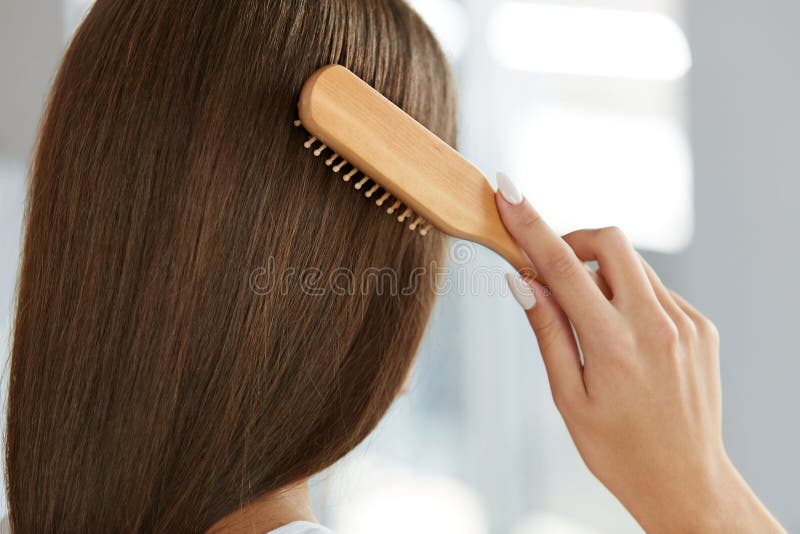 Beautiful Healthy Hair. Closeup Of Woman Hand Brushing Natural Long Brown Hair With Wooden Brush. Back View Of Woman Head Hairbrushing Using Hairbrush. Hair care Concept. High Resolution Image. Beautiful Healthy Hair. Closeup Of Woman Hand Brushing Natural Long Brown Hair With Wooden Brush. Back View Of Woman Head Hairbrushing Using Hairbrush. Hair care Concept. High Resolution Image